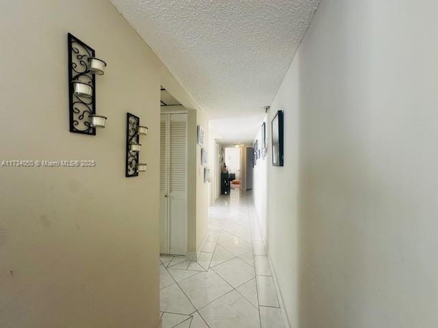 hall featuring light tile patterned floors and a textured ceiling