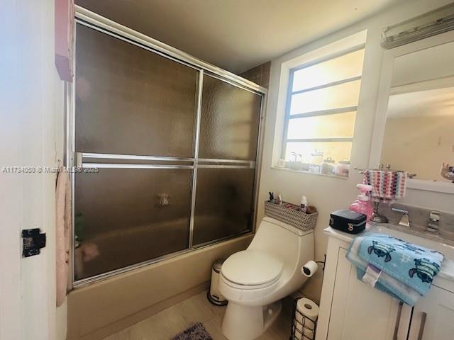 full bathroom with toilet, shower / bath combination with glass door, and sink