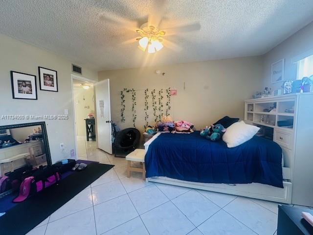 tiled bedroom featuring ceiling fan and a textured ceiling