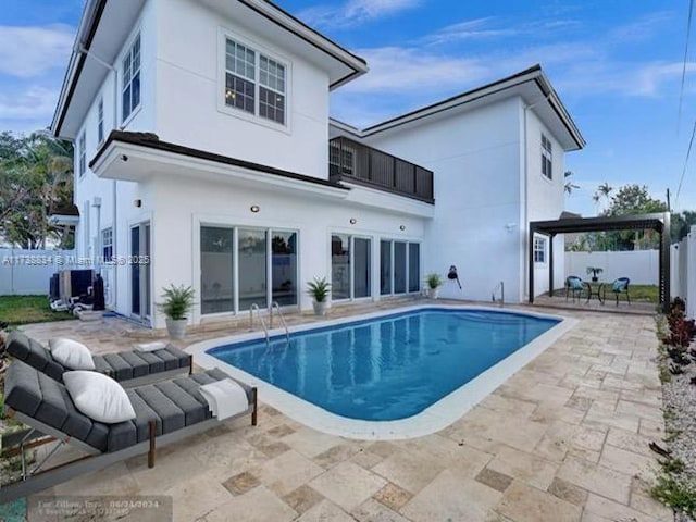 back of property with a fenced in pool, a patio area, and a balcony