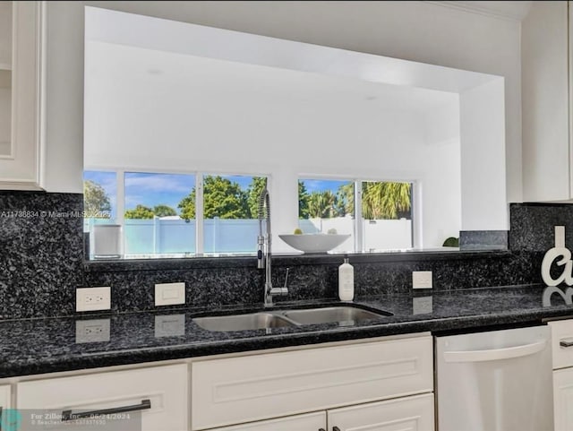 kitchen featuring dishwasher, sink, dark stone countertops, and white cabinets