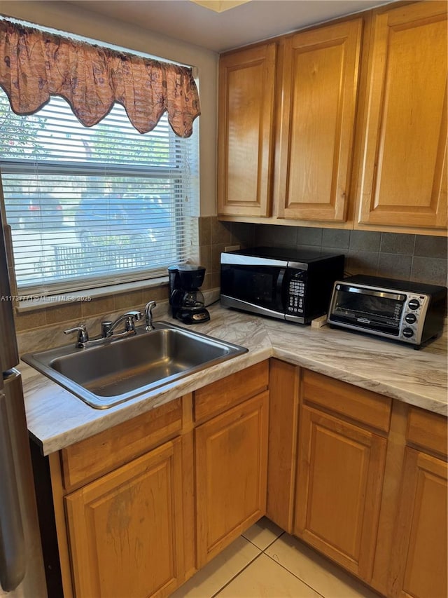 kitchen with light tile patterned flooring, sink, and backsplash