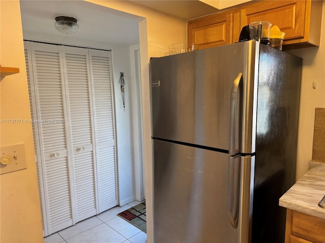 kitchen with light tile patterned floors and stainless steel refrigerator