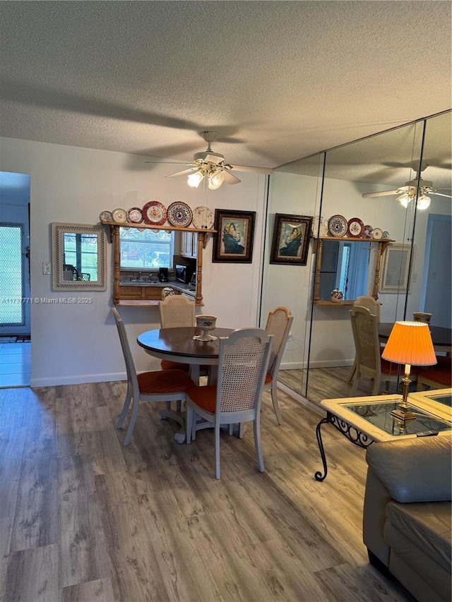 dining room featuring hardwood / wood-style flooring, ceiling fan, and a textured ceiling