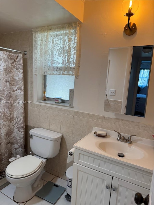 bathroom with tile walls, tile patterned flooring, plenty of natural light, vanity, and toilet