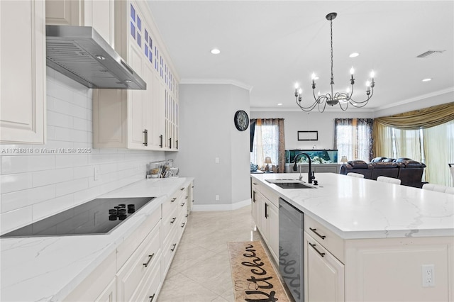 kitchen with an island with sink, sink, light stone countertops, wall chimney range hood, and black electric cooktop