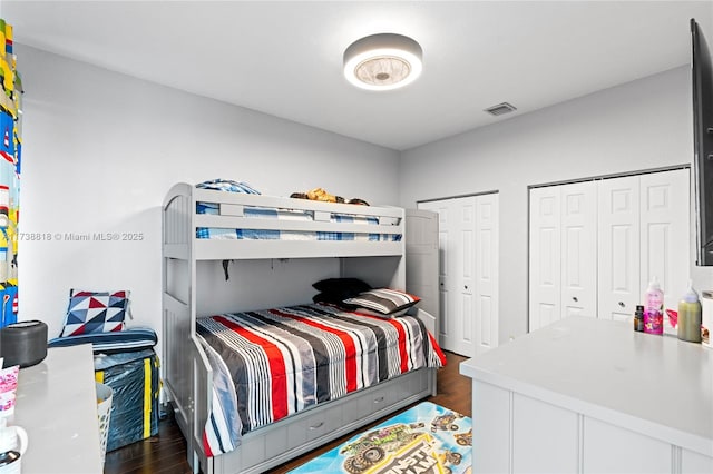 bedroom with dark hardwood / wood-style flooring and multiple closets