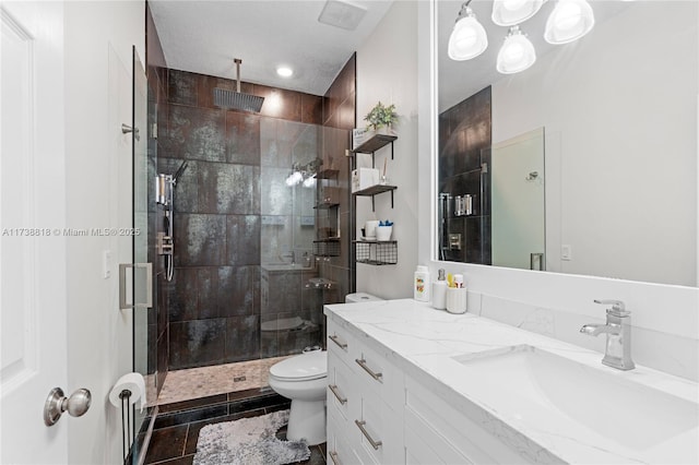 bathroom with a shower with door, vanity, tile patterned floors, and toilet