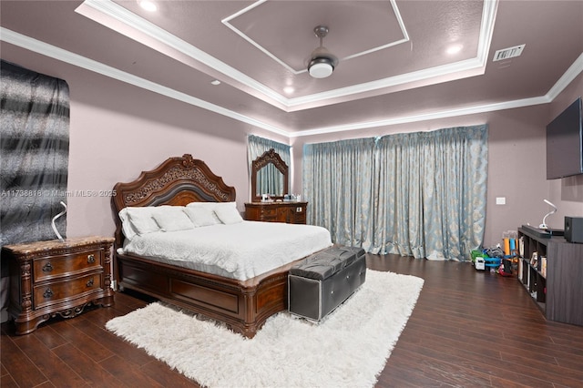 bedroom featuring ornamental molding, dark hardwood / wood-style floors, and a tray ceiling