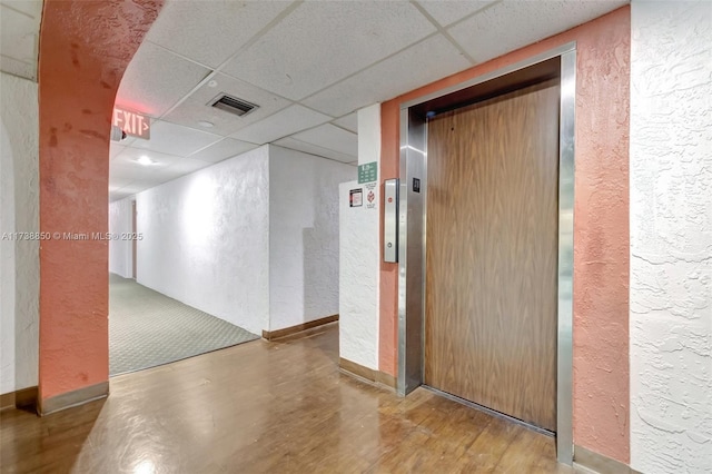 corridor featuring hardwood / wood-style floors, elevator, and a drop ceiling