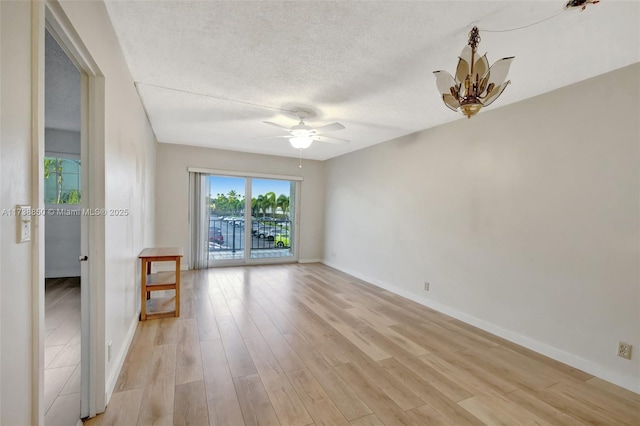 unfurnished room featuring ceiling fan with notable chandelier, a textured ceiling, and light wood-type flooring