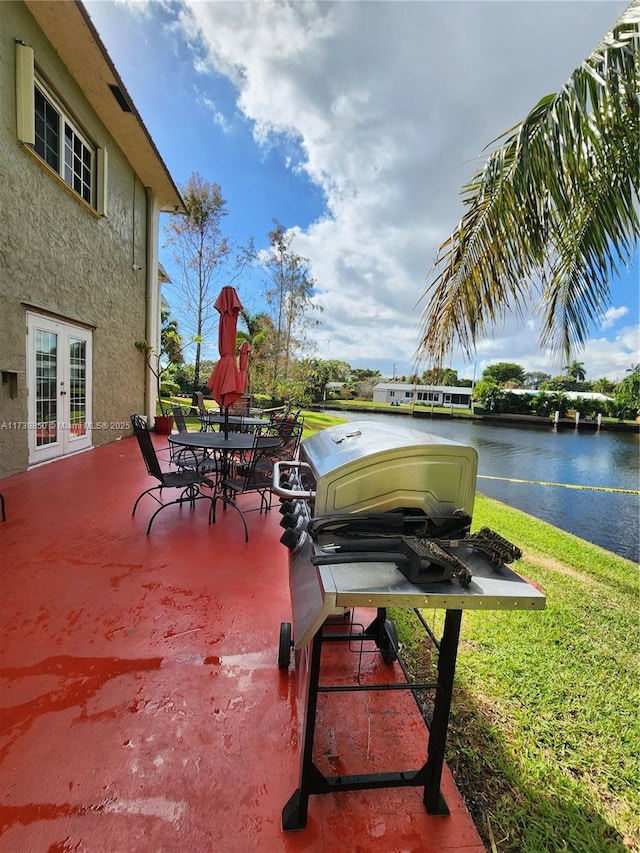 view of patio / terrace with french doors, a water view, and a grill