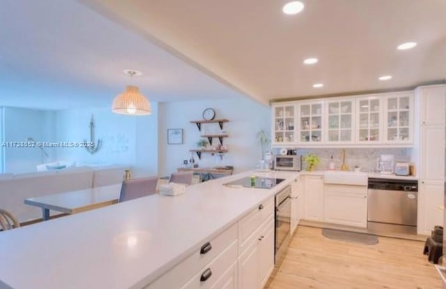 kitchen featuring dishwasher, white cabinetry, light hardwood / wood-style floors, black electric cooktop, and decorative light fixtures