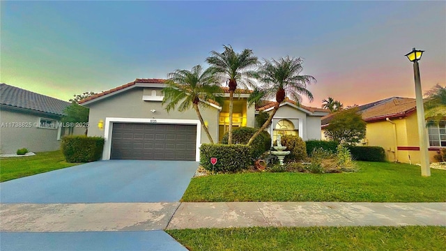 mediterranean / spanish-style home featuring a yard and a garage