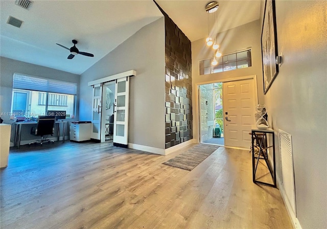 foyer featuring ceiling fan, a healthy amount of sunlight, high vaulted ceiling, and light hardwood / wood-style flooring