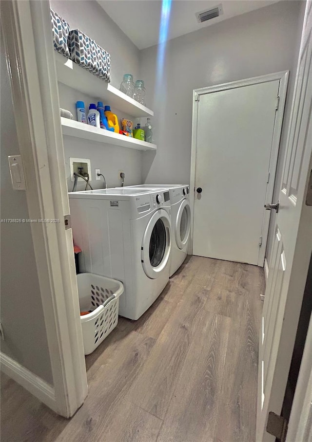 laundry area with independent washer and dryer and light wood-type flooring