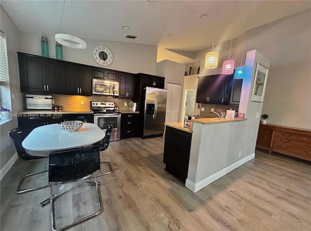 kitchen featuring pendant lighting, a breakfast bar area, kitchen peninsula, and appliances with stainless steel finishes