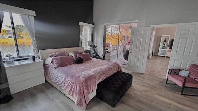 bedroom featuring a water view, access to exterior, and hardwood / wood-style floors