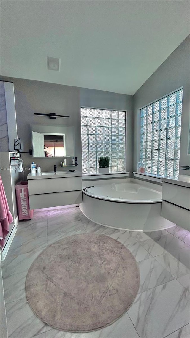 bathroom with vanity, a washtub, and plenty of natural light