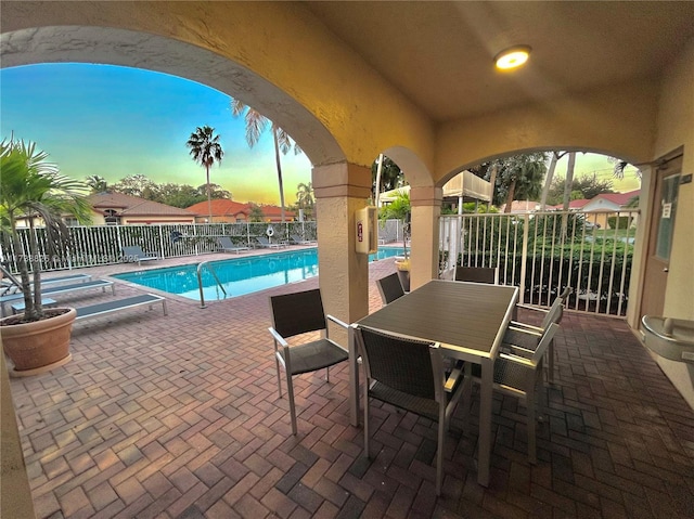 pool at dusk with a jacuzzi and a patio area