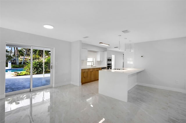 kitchen featuring pendant lighting, sink, white cabinets, kitchen peninsula, and black electric cooktop