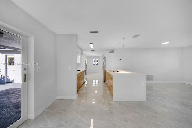 kitchen featuring stainless steel refrigerator, light brown cabinetry, and a center island