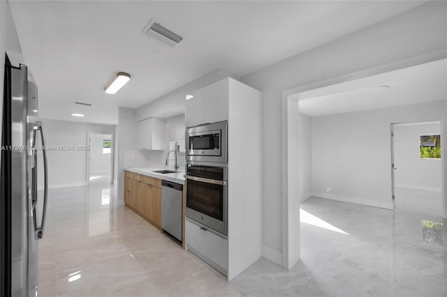 kitchen featuring appliances with stainless steel finishes, sink, and white cabinets