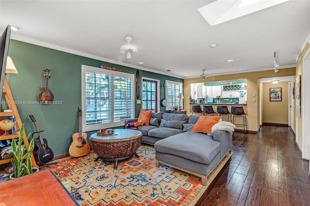 living room with a skylight, ornamental molding, dark hardwood / wood-style floors, and ceiling fan