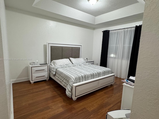 bedroom with dark hardwood / wood-style floors and a textured ceiling