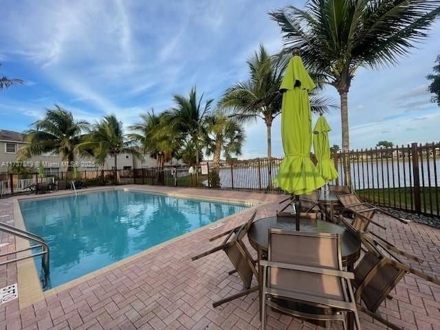 view of swimming pool with grilling area, a patio, and a water view