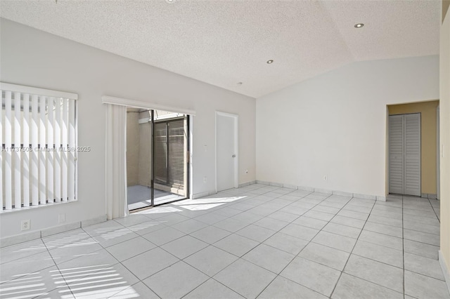 tiled empty room featuring lofted ceiling and a textured ceiling