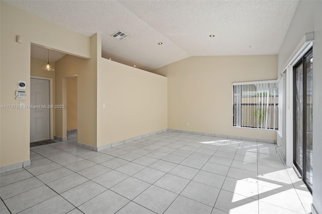 empty room featuring light tile patterned flooring, lofted ceiling, and a textured ceiling