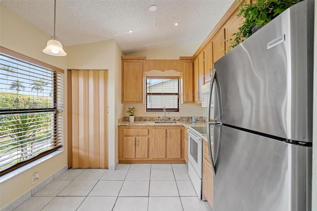 kitchen featuring light brown cabinetry, sink, decorative light fixtures, stainless steel refrigerator, and white electric stove