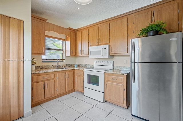 kitchen featuring sink, white appliances, light tile patterned floors, light stone countertops, and a textured ceiling