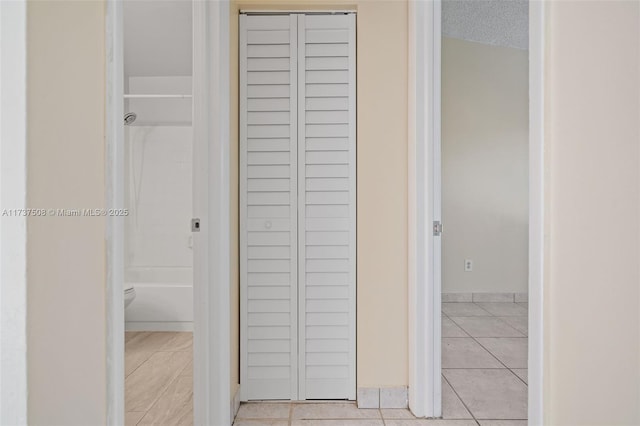 hallway with light tile patterned flooring and a textured ceiling