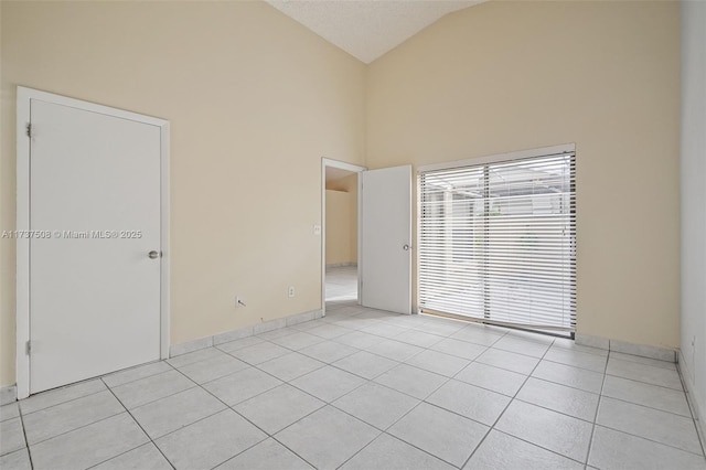 spare room featuring light tile patterned floors and high vaulted ceiling