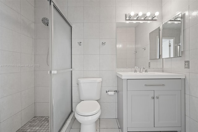 bathroom featuring walk in shower, tile patterned floors, toilet, tile walls, and vanity