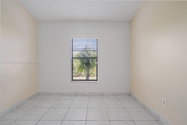 spare room featuring light tile patterned floors and a textured ceiling