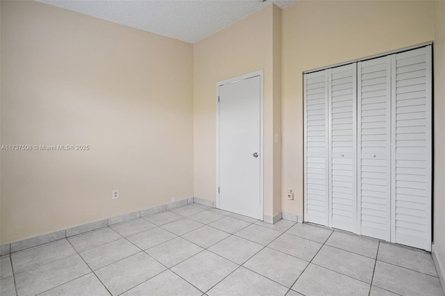 unfurnished bedroom with light tile patterned floors, a textured ceiling, and a closet