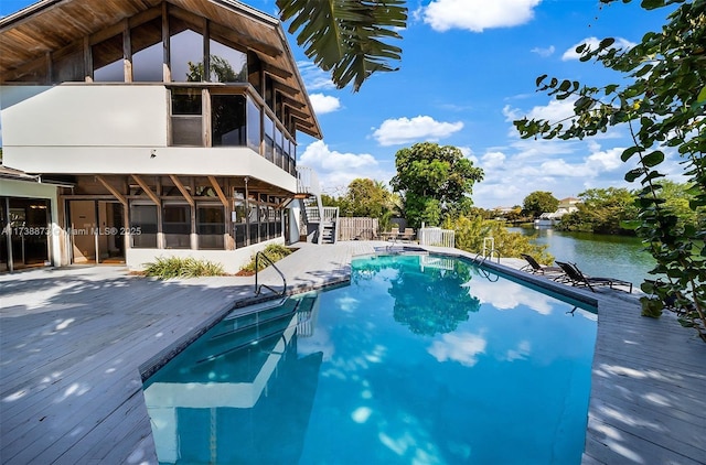 view of swimming pool with a sunroom and a deck with water view