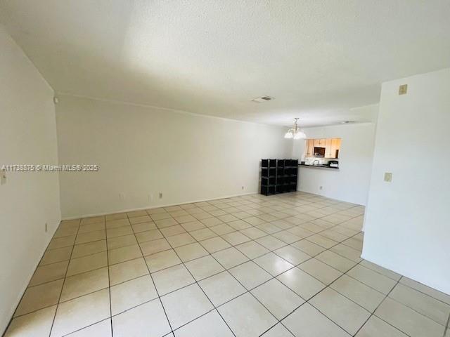 tiled empty room featuring a textured ceiling