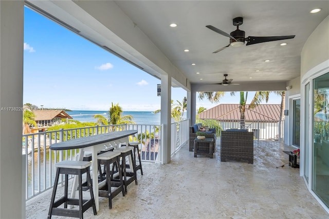 view of patio with a balcony, ceiling fan, and a water view