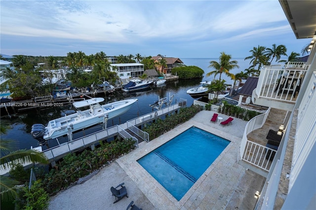 view of swimming pool featuring a patio area, a boat dock, and a water view