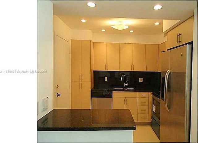 kitchen with stainless steel appliances, light brown cabinetry, sink, and backsplash