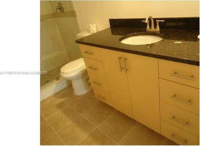 bathroom featuring vanity, toilet, tile patterned flooring, and a tile shower