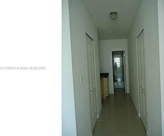 hallway with light tile patterned floors and a textured ceiling