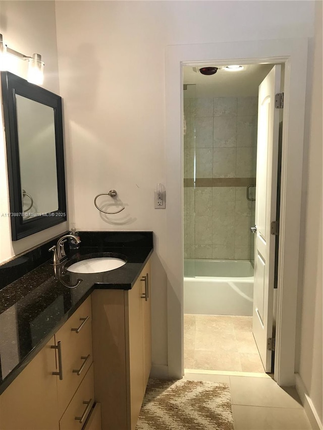 bathroom with tiled shower / bath combo, vanity, and tile patterned flooring