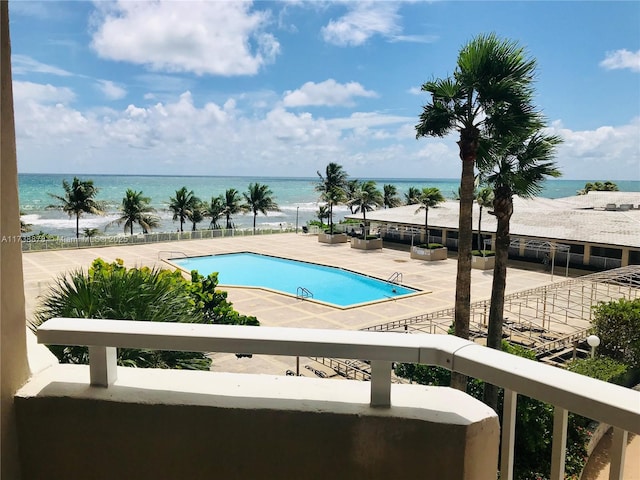 view of swimming pool featuring a patio, a water view, and a beach view