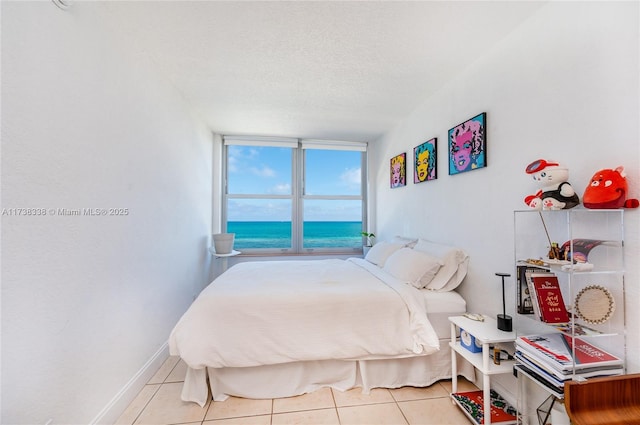 tiled bedroom with a textured ceiling and a water view