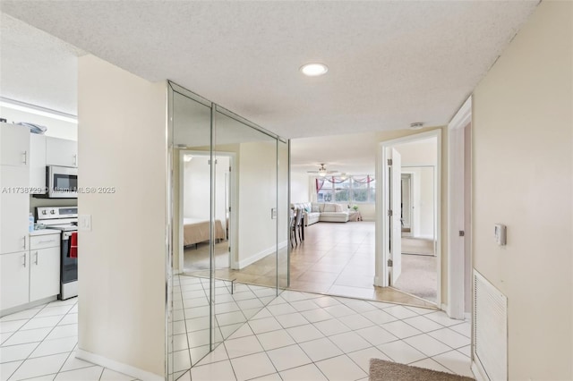 hall with a textured ceiling and light tile patterned floors